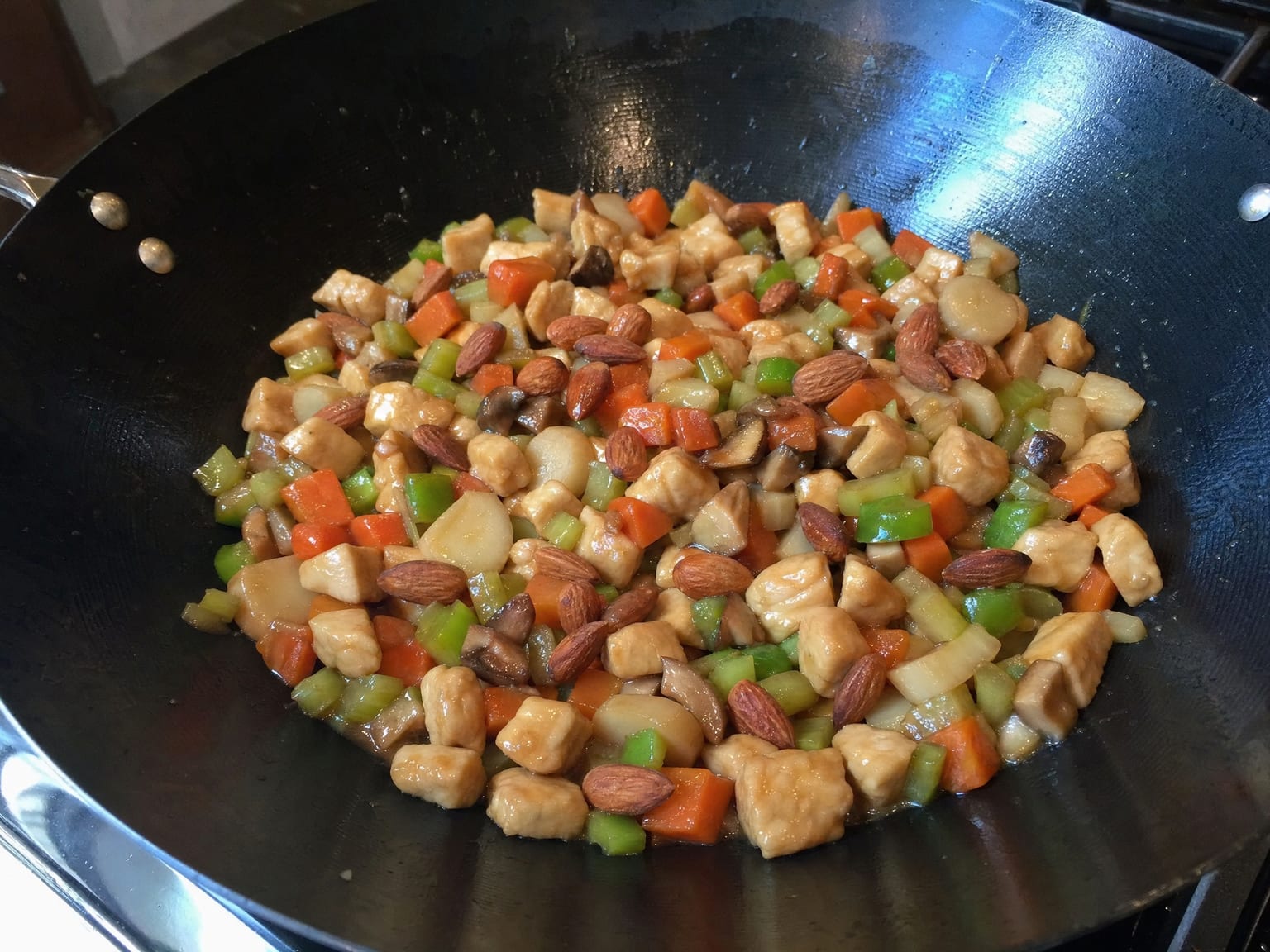 Diced chicken with diced carrot, celery and pepper in a light glossy sauce scattered with whole almonds
