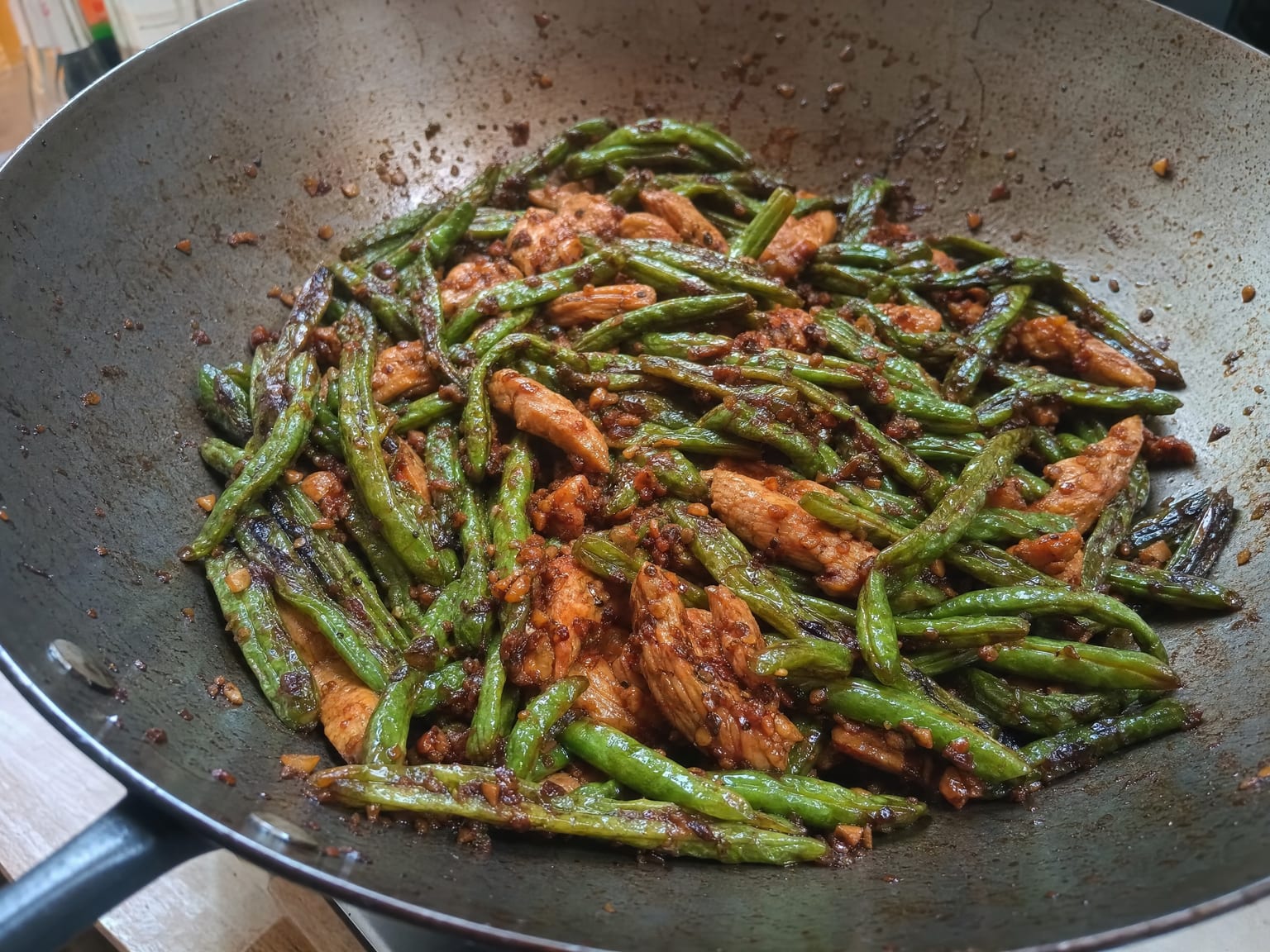 Blistered wrinkled green beans with sliced chicken and minced garlic in a dark savoury sauce