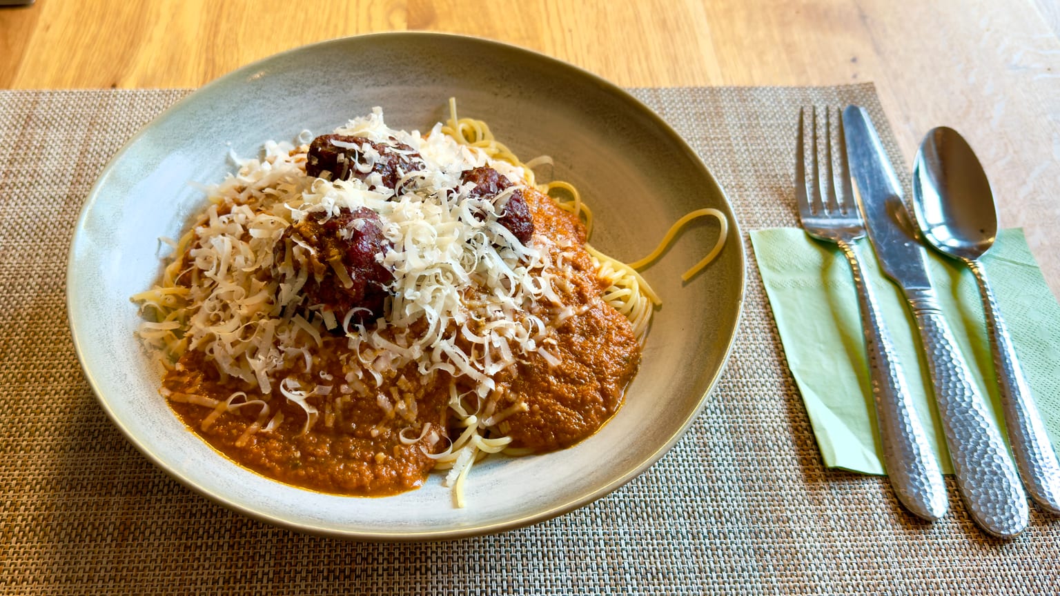 Smoked meatballs over spaghetti with tomato sauce, topped with a heavy pile of grated hard cheese