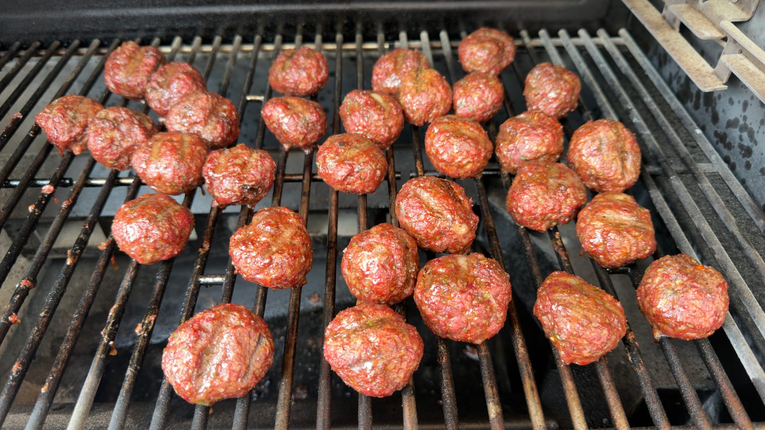 Rows of smoked meatballs on the grate of a Gravity XT smoker