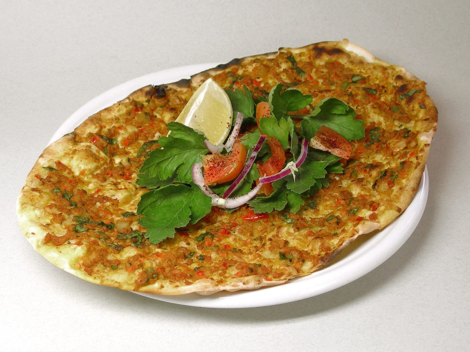Dünnes türkisches Lahmacun mit würzigem Hackfleischbelag bei natürlichem Licht