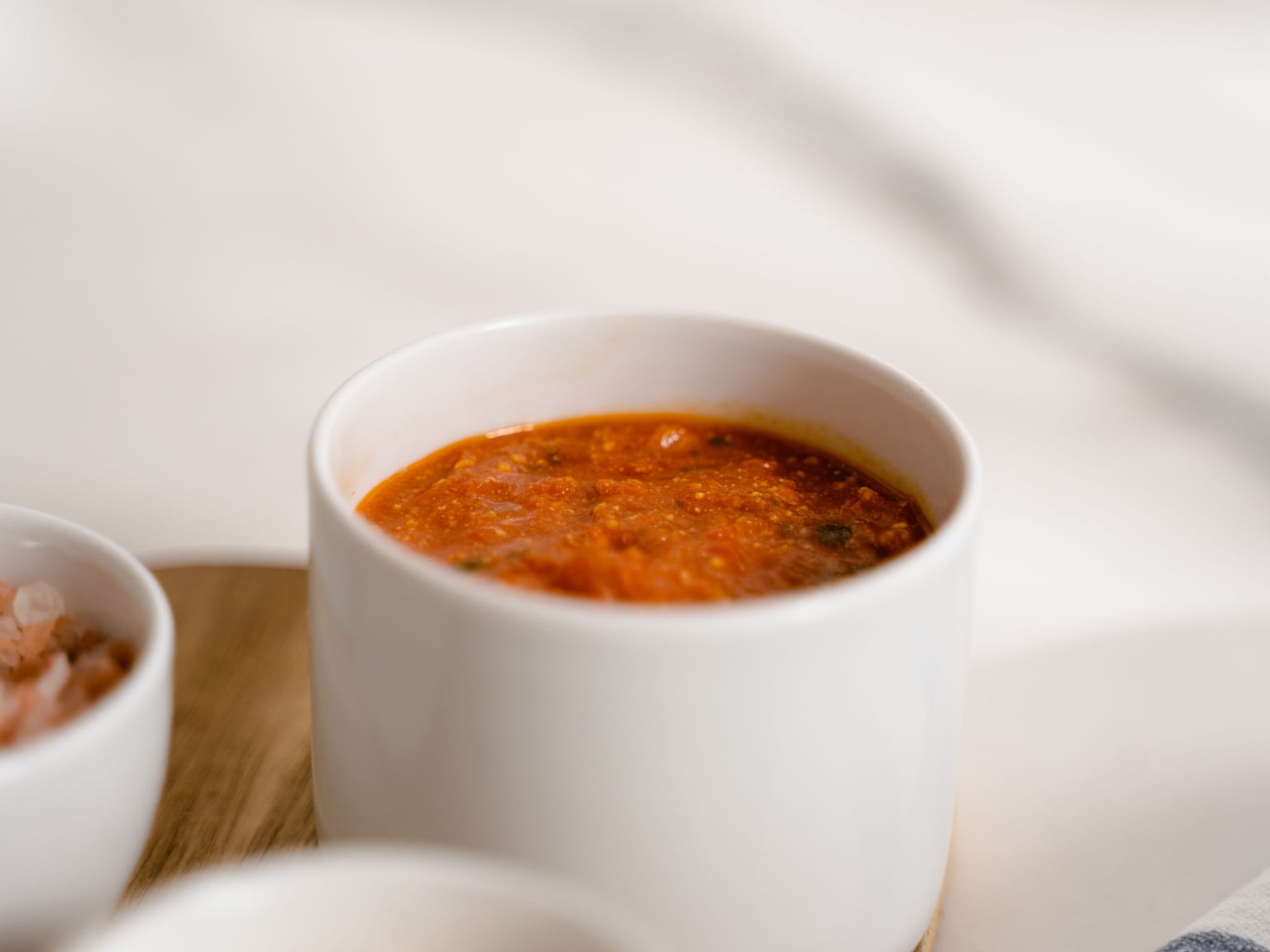 Rustikale italienische Tomatensauce in einer flachen Schale mit sichtbarem Knoblauch und gezupftem Basilikum