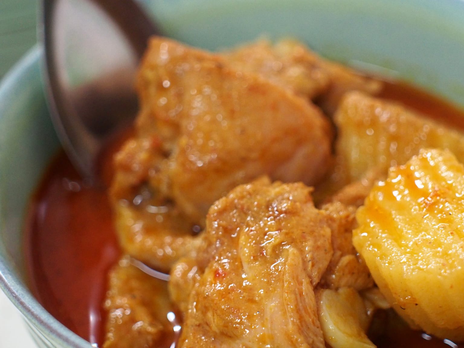 Massaman curry in a wide shallow bowl on a cream cloth, chicken and potato in a thick tan coconut sauce, chopped peanuts and a cinnamon stick on top, jasmine rice alongside