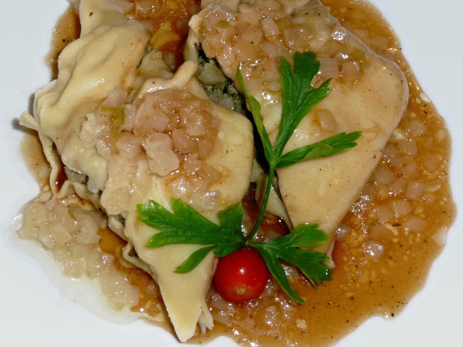 Maultaschen in a shallow cream bowl of clear broth, sliced Frühlingszwiebeln scattered over, soft natural light from the side