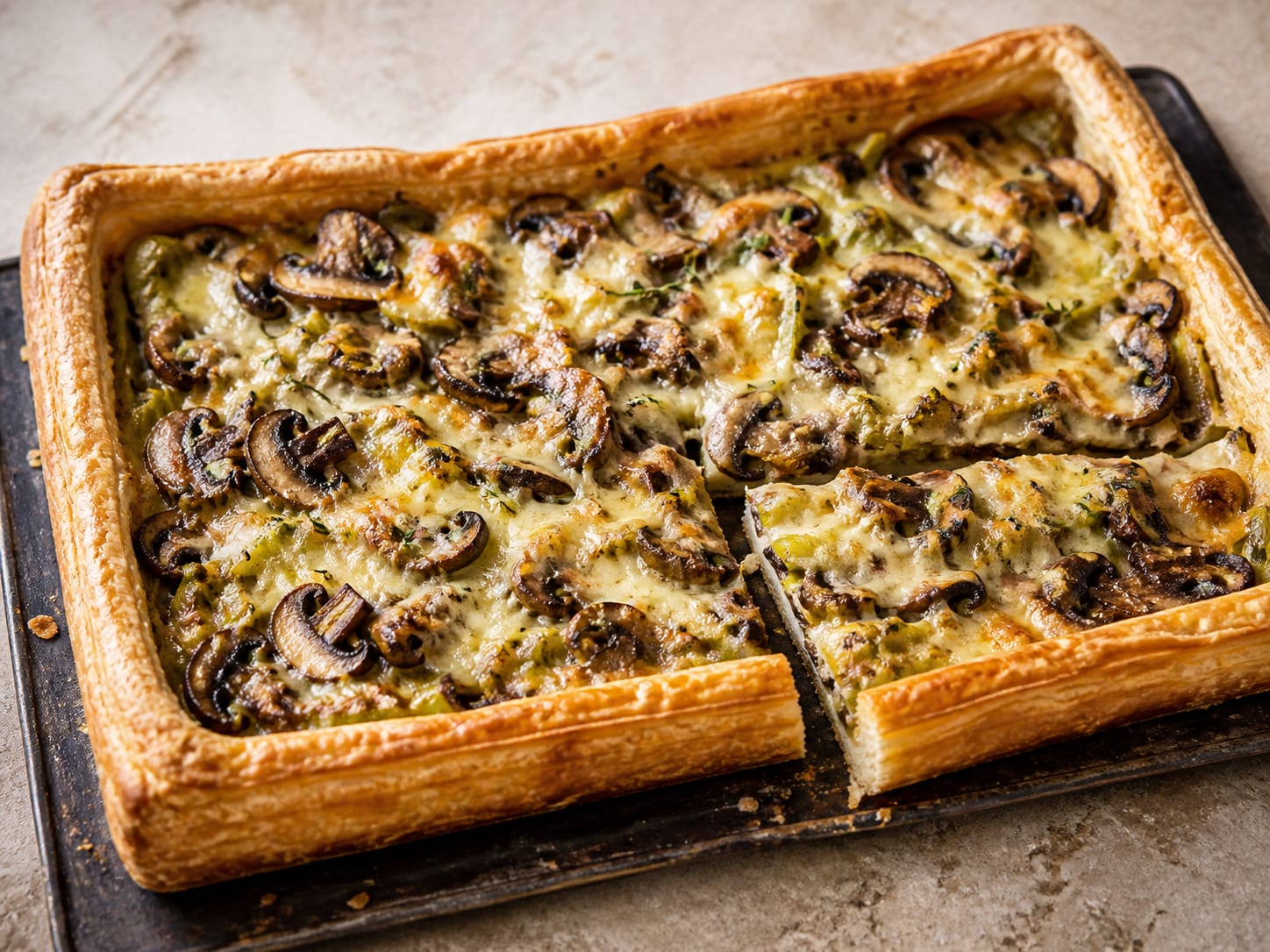 Mushroom, leek, and Gruyère puff tart served as a natural-light editorial food photograph