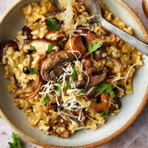 Eine Schüssel cremiges Pilzrisotto mit gebräunten gemischten Pilzen und Petersilie