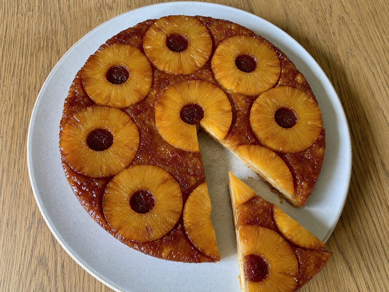 A pineapple tarte tatin flipped onto a plate, golden caramelized rings arranged in a circle