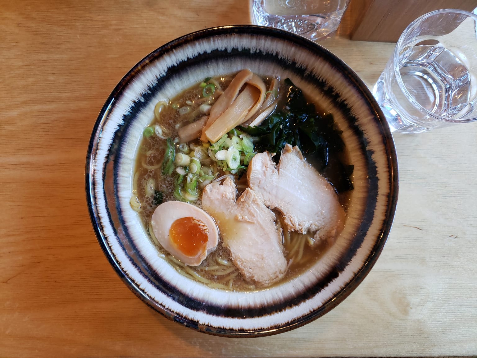 A clear soy-seasoned ramen broth with noodles, a halved soft egg, nori and scallions