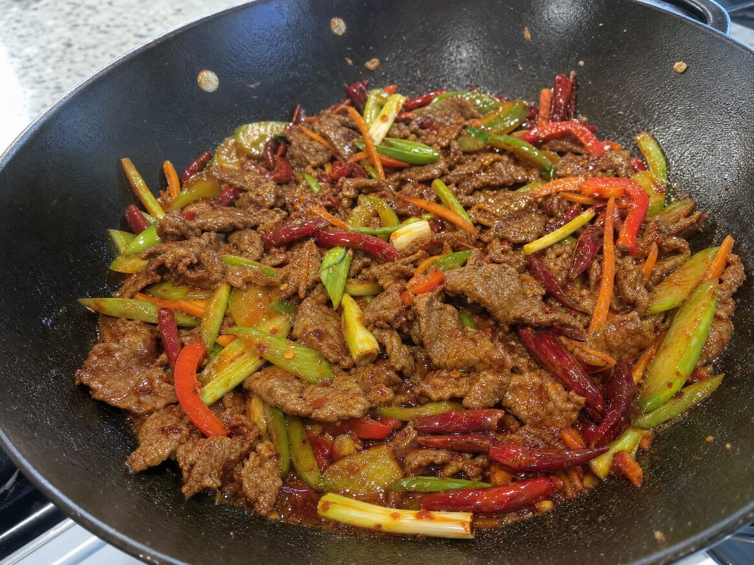 Sliced beef with carrot, celery and pepper strips in a glossy red chilli sauce with dried chillies